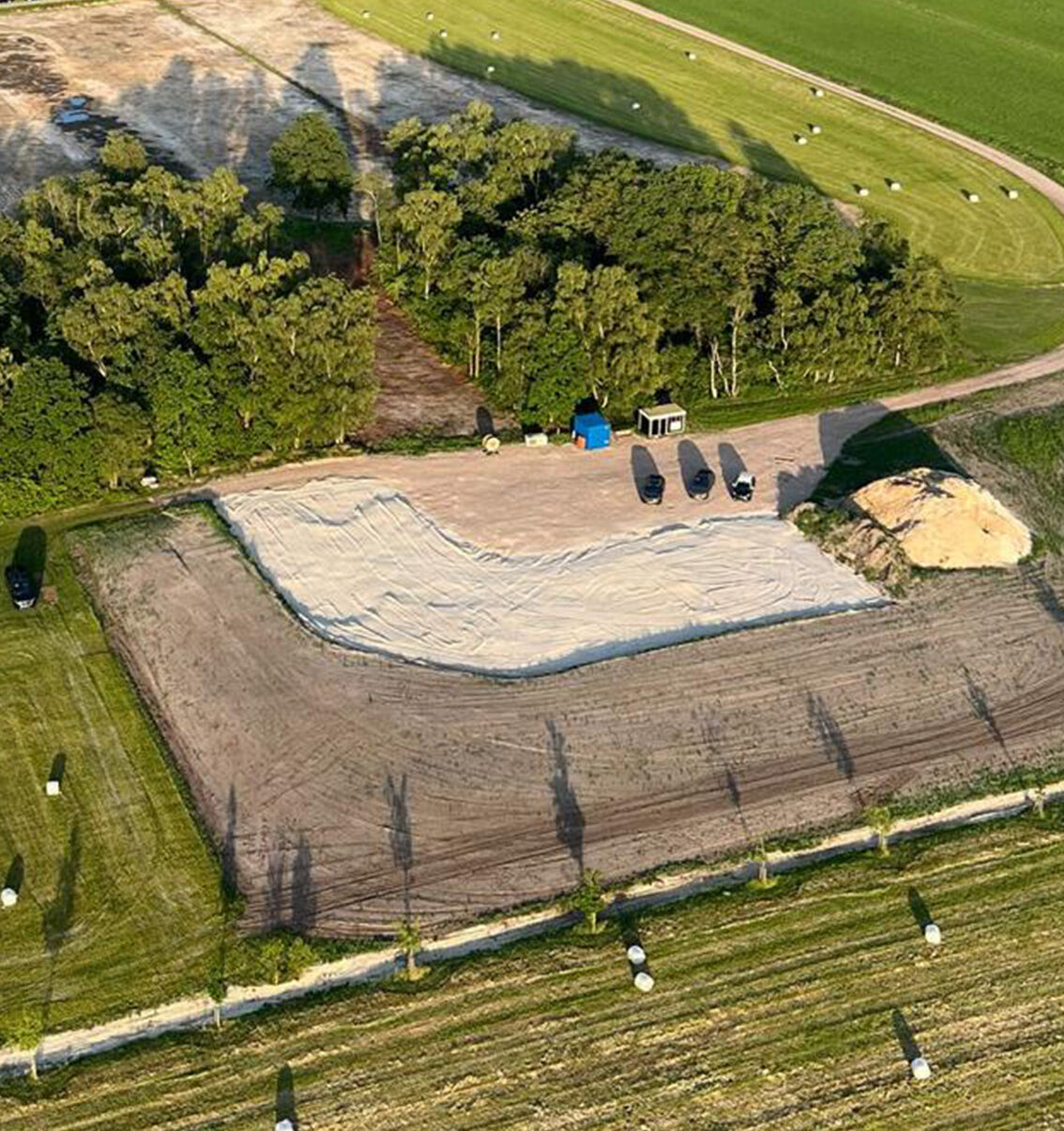 Eigentijdse woning op een landgoed met lichte gevels, donkere kap, grote glaspartijen en een groen landschap op de achtergrond.